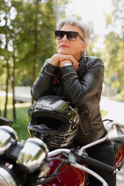 Photo side view cool old woman with motorcycle