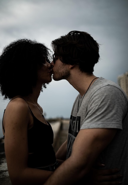 Photo side view of couple kissing man outdoors