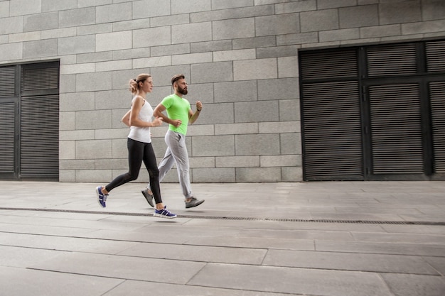 Side view of couple running in an urban environment