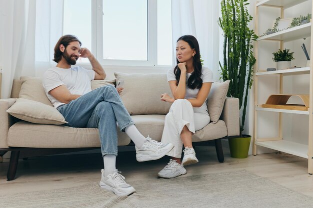 Photo side view of couple sitting on sofa at home