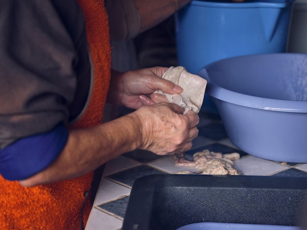Вид сбоку на неузнаваемого фермера в фартуке, готовящего оболочки, стоящего за столом во время изготовления колбасы в традиционной бойне на Майорке