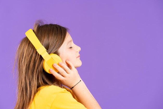 Side view of cute little girl listening to music