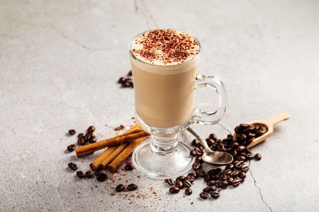 Side view on decorated coffee latte with cacao in a glass mug on the concrete background