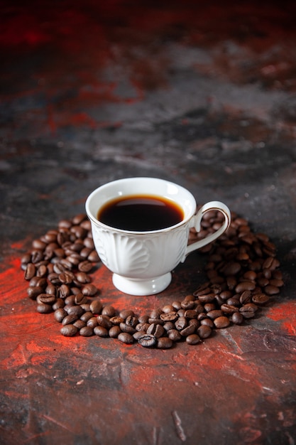 Вид сбоку на вкусный кофе в белой чашке и обжаренные зерна вокруг него на смешанном цветном фоне со свободным пространством