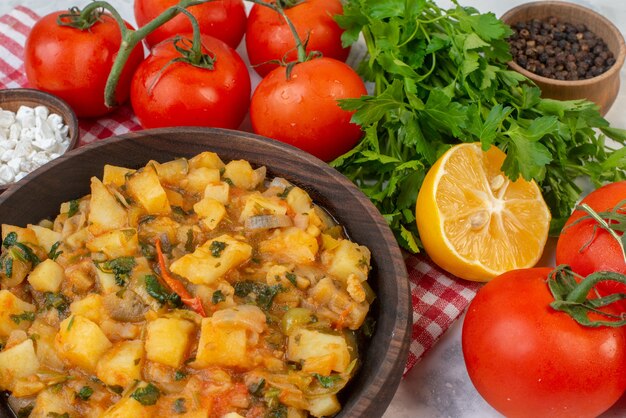 Side view of delicious dinner with potatoes green in a brown bowl on red stripped towel tomatoes with stems pepper green bundle