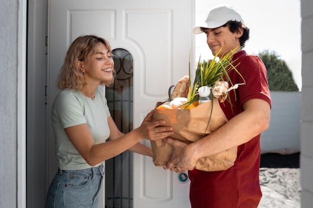 Photo side view delivery man with groceries