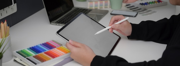 Side view of designer drawing on mock-up tablet with stylus pen