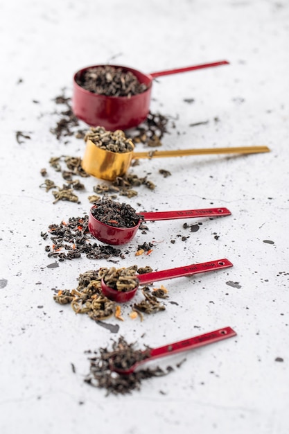 Side view on different measure spoons with black tea on the white background