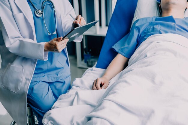 Side view of diverse doctors examining Asian female patient in bed in ward at hospital