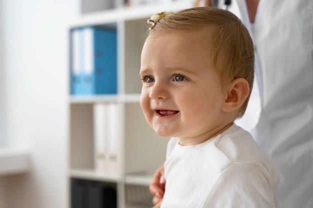 Photo side view doctor holding smiley baby