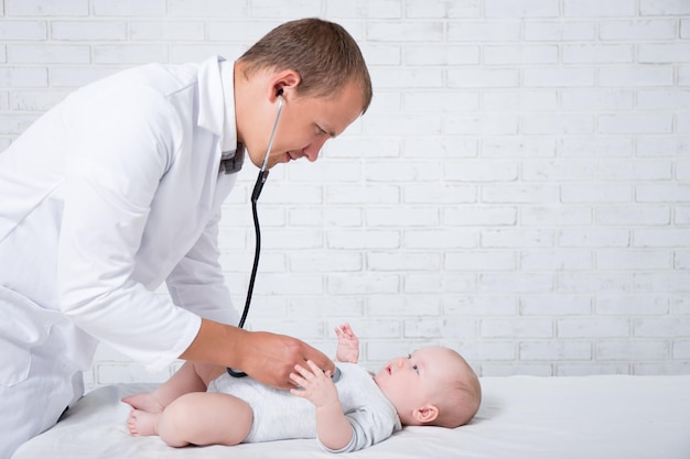 Side view of doctor pediatrician examining little baby patient in hospital