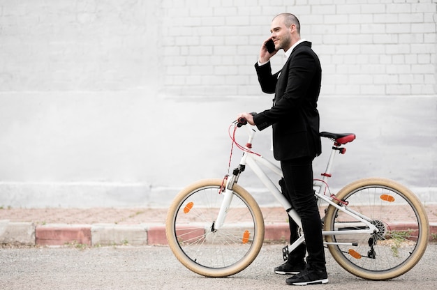 Foto maschio elegante di vista laterale con la bicicletta all'aperto