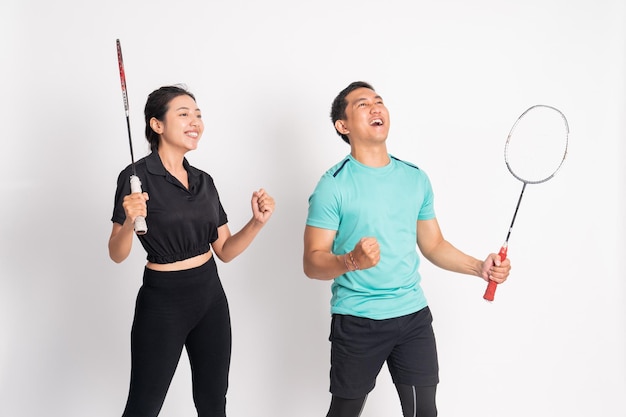 side view of excited woman and man standing holding racket on isolated background