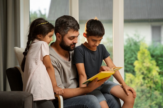 Foto vista laterale del padre che legge ai bambini