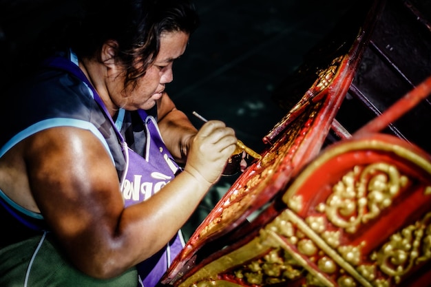 Photo side view of female artist working on wood at workshop