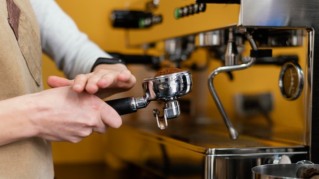 Photo side view of female barista using coffee machine