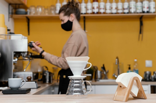 Side view of female barista with mask working at the coffeehouse