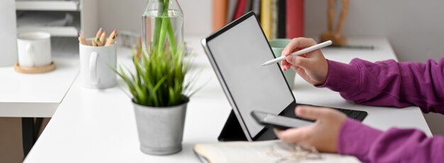 Side view of female college student doing assignment with mock-up table, smartphone and stationery