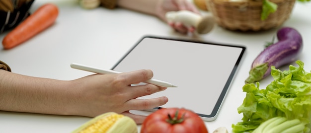 Side view of female cook online ordering ingredients on blank screen tablet