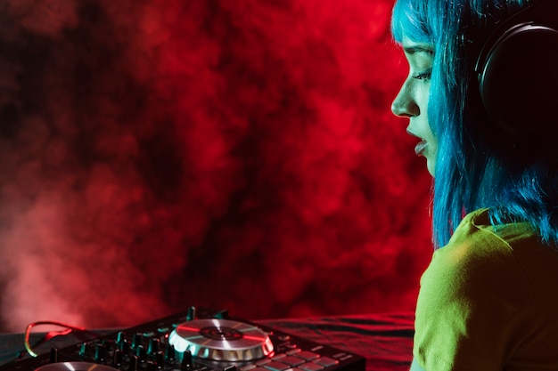 Side view female dj mixing and covered in red smoke