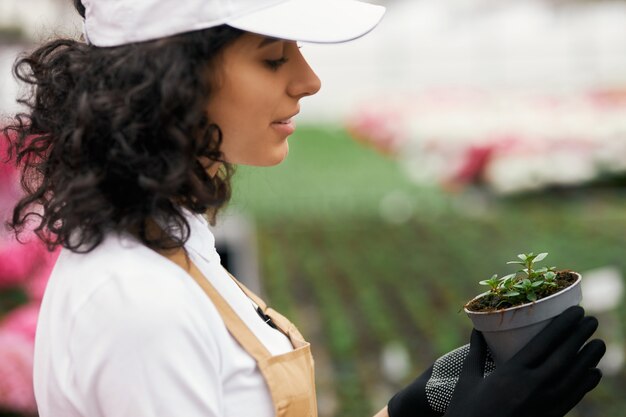 Side view of female gardener holding pot with green plant