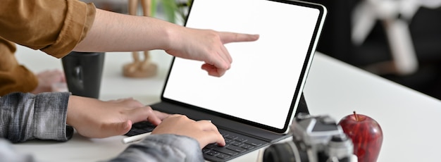 Photo side view of female graphic designer typing on digital tablet on worktable