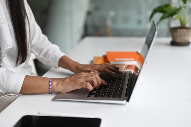 Side view of female office worker working on laptop at modern office.