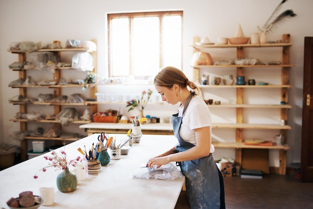 Photo side view of female potter working at workshop