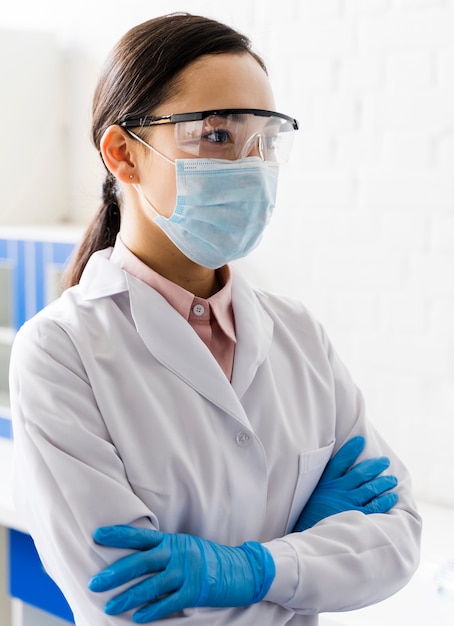 Foto vista laterale della scienziata con maschera medica e guanti chirurgici in laboratorio