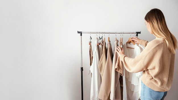 Photo side view of female tailor checking garments on hangers with copy space