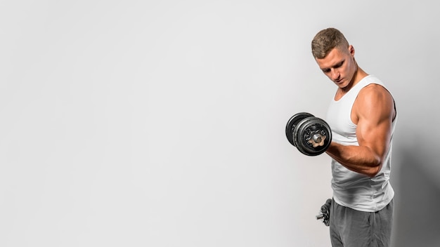 Photo side view of fit man with tank top using weights