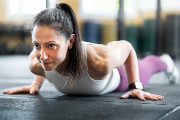 Donna adatta di vista laterale che fa burpees