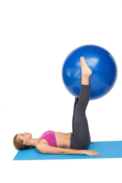 Side view of a fit woman exercising with fitness ball