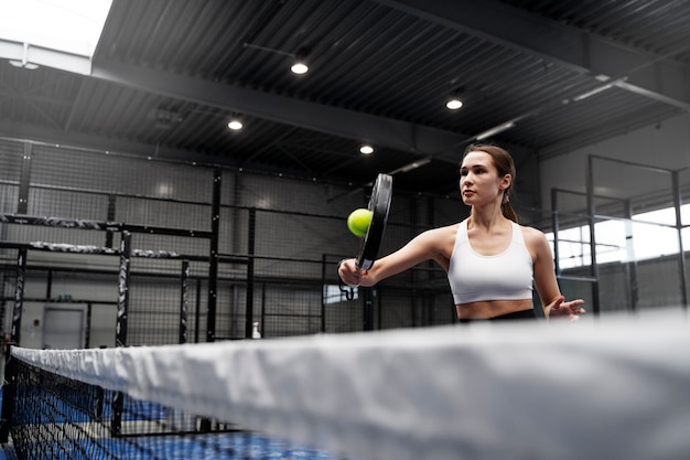 Photo side view fit woman playing paddle tennis