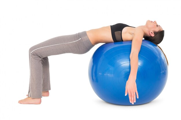 Side view of a fit woman stretching on fitness ball