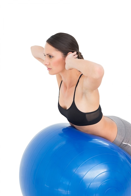 Side view of a fit woman stretching on fitness ball