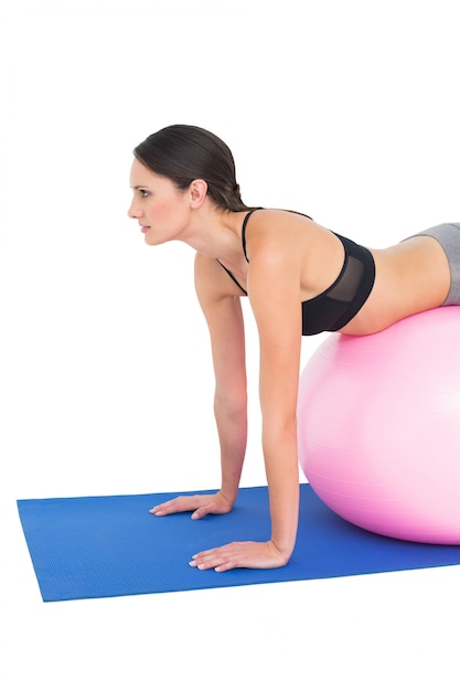 Side view of a fit woman stretching on fitness ball