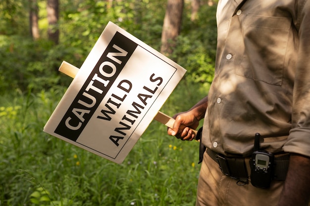 Photo side view forest warden holding warning sign