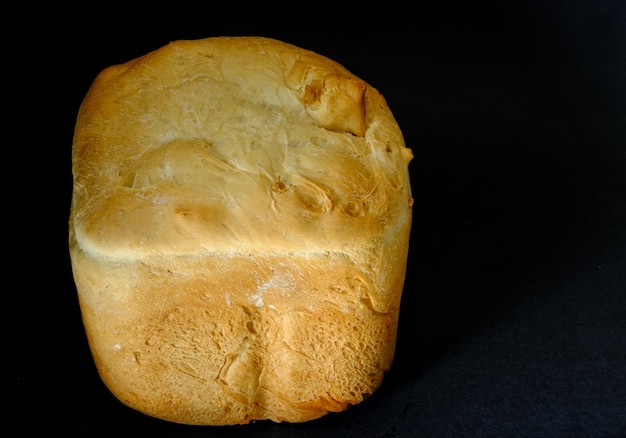Side view of fresh tall white loaf of bread on black background