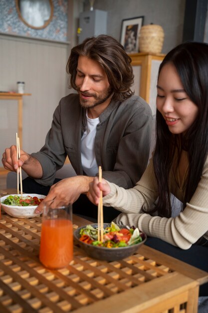 Photo side view friends eating salmon bowls