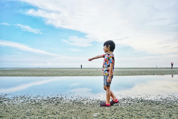 Side view full length of boy standing at beach