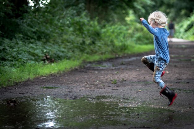 Side view full length of girl playing in puddle