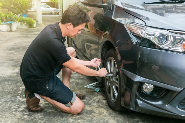 Photo side view full length of man removing tire of car