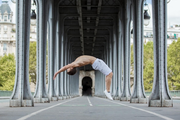 side view full length of shirtless man jumping below bridge