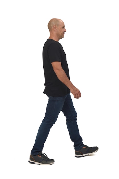 Side view of a full portrait of a bald man walking on white background