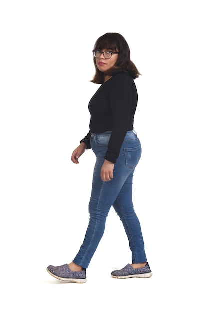 Photo side view of a full portrait of a latin woman walking and looking at camera on white background