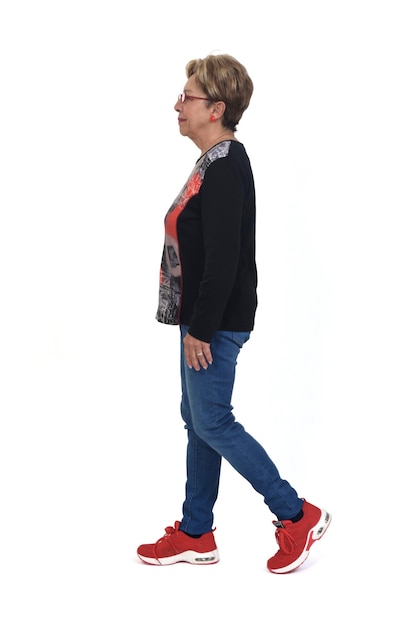 Photo side view of full portrait of a senior woman walking on white background