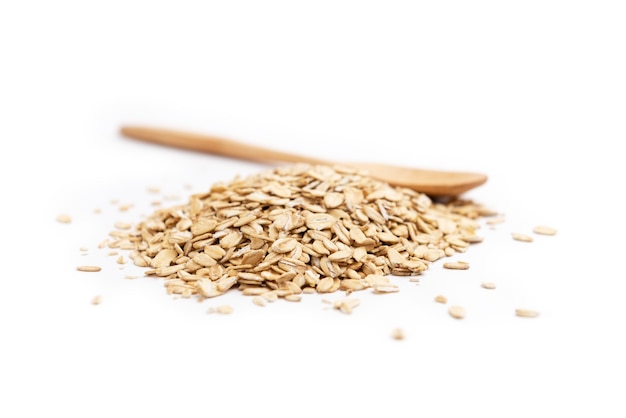 Side view of a full wooden spoon and a pile of oat flakes isolated.