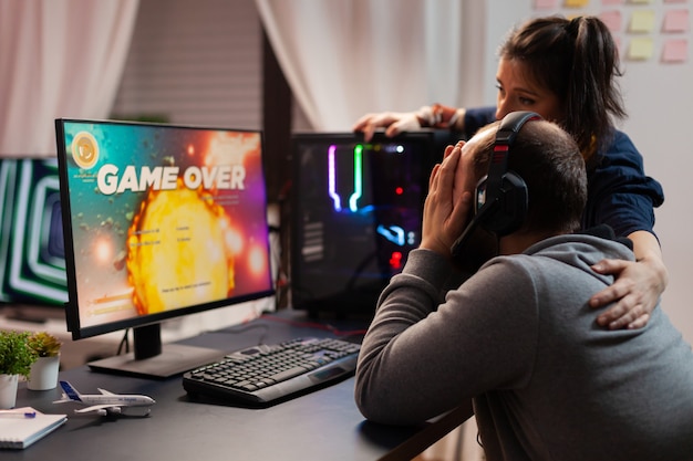 Side view of game over for pro player couple, playing space
shooter games. defeated man streaming online cyber performing
during gaming tournament