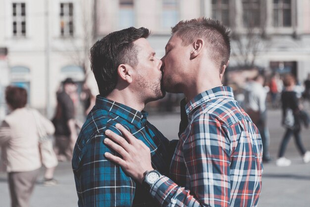 都市で口でキスしているゲイカップルの横の景色